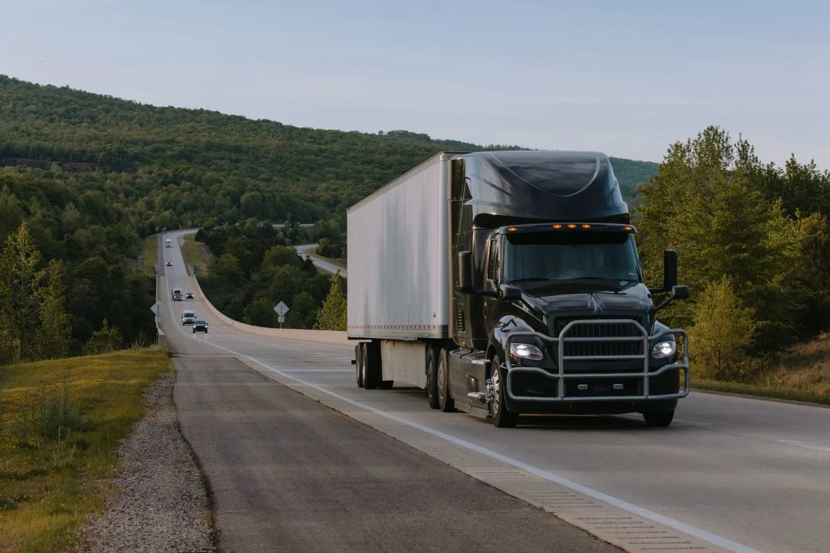 Black truck with white trailer driving down a scenic road