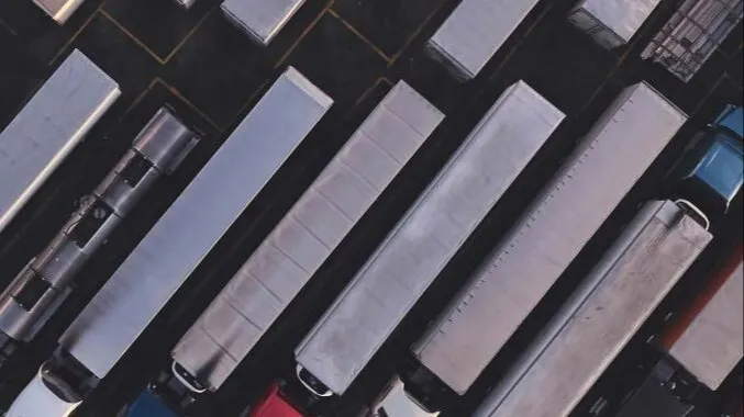 Aerial view of semi-trucks and trailers lined up diagonally in a parking lot or shipping yard
