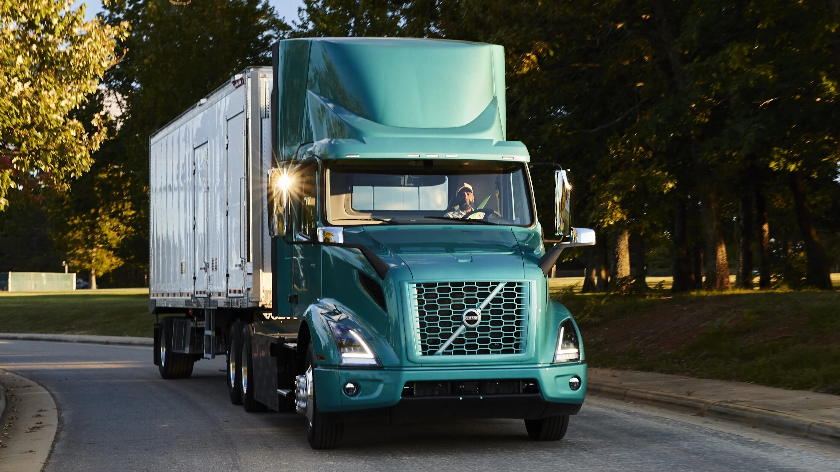 Green truck driving on road.
